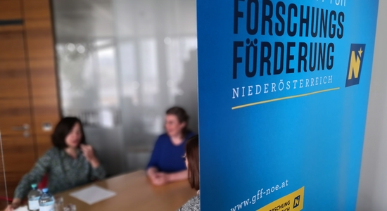 Besprechung der Mitarbeiter mit Logo Roll-up im Vordergrund